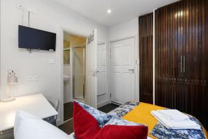 a room with a bed and a desk and a television at Single Studio Flat in London