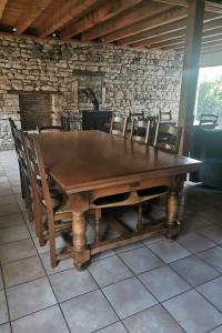 a wooden table and chairs in a room with a stone wall at Les Gites de Louisette Le 974 in Ébreuil