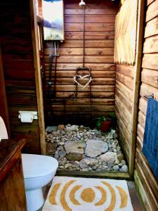 a bathroom with a toilet and rocks in a room at Pura Vida Forest Cabin in Witelsbos