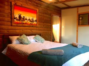 1 dormitorio con 1 cama con una pintura en la pared en Pura Vida Forest Cabin, en Witelsbos