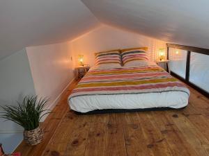 1 dormitorio con 1 cama con manta a rayas y 2 lámparas en Studio Duplex Montmorillon, en Montmorillon