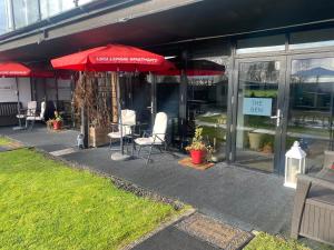 a restaurant with tables and chairs and a red umbrella at loch lomond apartments in Alexandria