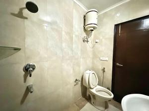 a bathroom with a toilet and a light on the wall at jacuzzi & spacious open terrace with room & bonfire in Gurgaon