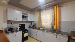 a kitchen with white cabinets and a black appliances at Hotfoot Homestay in Nanyuki