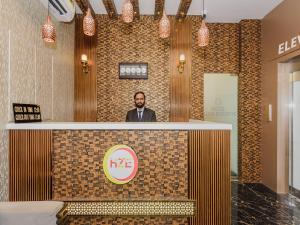 a man standing behind a counter in a lobby at Hotel Zillion Executive - Kurla West Mumbai in Mumbai