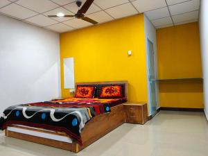 a bedroom with a bed with a yellow wall at Madhav Farmhouse in Sasan Gir
