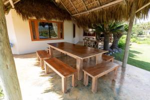 una mesa de madera y bancos en un patio en Villa Punta Coral, en Las Galeras
