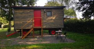 a tiny house with a red door and a table at Roulotte - Etat Nature in Magnières