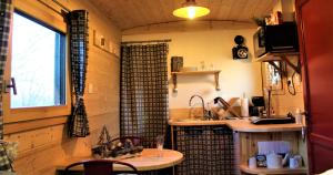 a kitchen with a table and a sink in a room at Roulotte - Etat Nature in Magnières