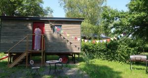 a woman standing at the door of a tiny house at Roulotte - Etat Nature in Magnières