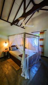 Schlafzimmer mit einem Bett mit Moskitonetz in der Unterkunft Hilltop House in Arugam Bay