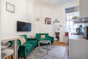 a living room with a green couch and a tv at DELUXE Two Bed in Covent Garden in London