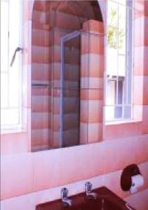 ein Badezimmer mit einem Spiegel und einem Waschbecken in der Unterkunft NSK GUEST HOUSE in Alberton