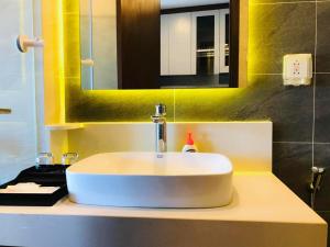 ein Badezimmer mit einem weißen Waschbecken und einem Spiegel in der Unterkunft Apec Mandala hotel & suites Hải dương in Hải Dương