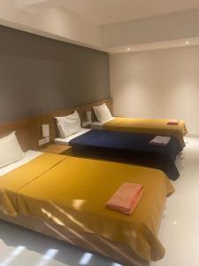 two beds in a room with yellow and blue at Sona Hotel in Trichūr