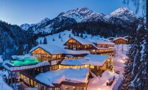 ein schneebedecktes Gebäude mit Bergen im Hintergrund in der Unterkunft Almwellness-Resort Tuffbad in Sankt Lorenzen im Lesachtal