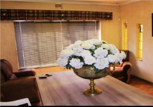 eine Vase weißer Blumen auf einem Tisch in der Unterkunft NSK GUEST HOUSE in Alberton