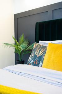 Una cama con una almohada amarilla y una planta en elegant apartment 3 en Milton Keynes