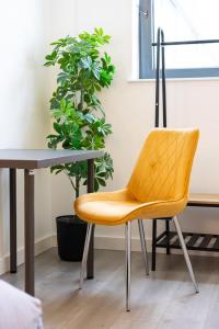 una silla amarilla junto a una mesa y una planta en elegant apartment 3 en Milton Keynes