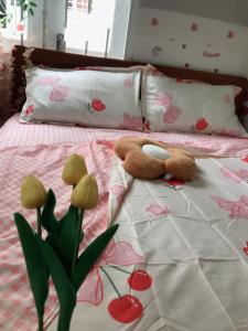a stuffed teddy bear laying on a bed with flowers at Lucky Home in Nha Trang