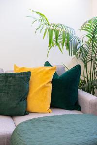 un sofá con almohadas verdes y amarillas. en elegant apartment 3 en Milton Keynes