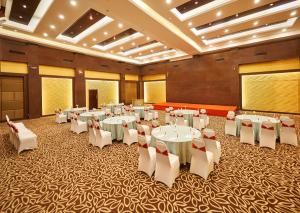 a banquet hall with white tables and white chairs at Hotel Halez in Chennai