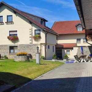 une maison avec des fleurs sur les fenêtres et un trottoir dans l'établissement Pension Lichtenauer Hof, à Thyrnau