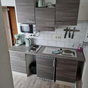 a small kitchen with a sink and a microwave at Wilhelm Busch Stube in Ebergötzen