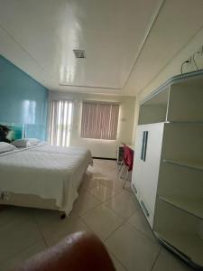 a bedroom with a white bed and a window at HOTEL NOVA AMÉRICA in Teixeira de Freitas