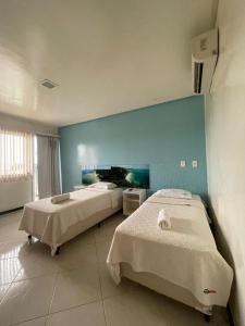 two beds in a room with a blue wall at HOTEL NOVA AMÉRICA in Teixeira de Freitas