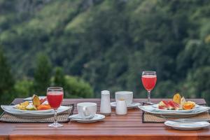 een houten tafel met borden eten en wijnglazen bij Hotel Onrock in Ella