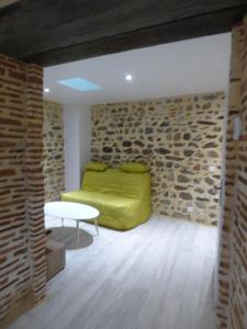 - un salon avec un canapé jaune et un mur en pierre dans l'établissement Désirée, à Brioude