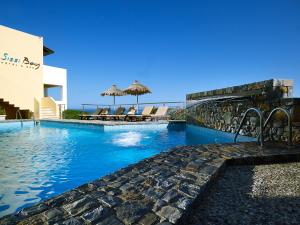 una piscina con sillas y sombrillas junto a un edificio en Sissi Bay Resort en Sissi