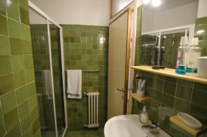 een groene betegelde badkamer met een wastafel en een douche bij Accogliente appartamento in Corso Italia in Cortina dʼAmpezzo