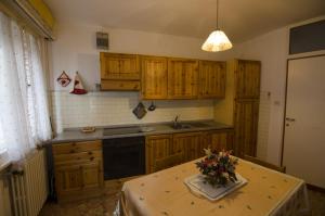 een keuken met houten kasten en een tafel met bloemen erop bij Accogliente appartamento in Corso Italia in Cortina dʼAmpezzo