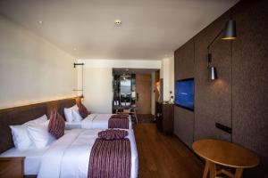 una camera d'albergo con due letti e una televisione di Ramada by Wyndham Diqing a Shangri-La
