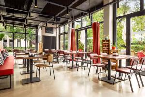 un restaurante con mesas, sillas y ventanas en Vienna House Easy by Wyndham München en Múnich