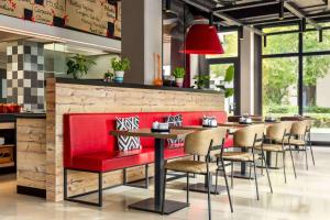 a restaurant with a red bench and tables and chairs at Vienna House Easy by Wyndham München in Munich