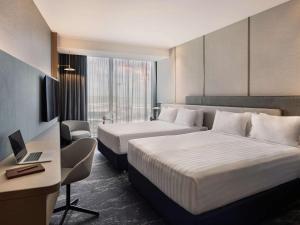 a hotel room with two beds and a desk at Pullman Auckland Airport in Auckland