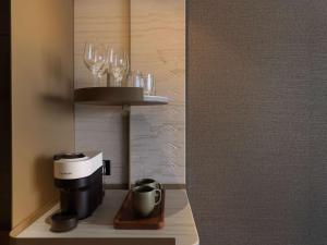 a room with a coffee maker and wine glasses on a shelf at Pullman Auckland Airport in Auckland