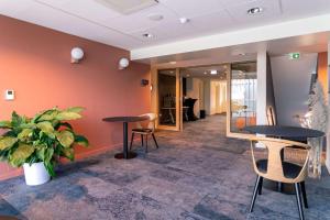 a lobby with two tables and chairs and a plant at Hotel Lille Euralille - Hilton Affiliate Hotel in Lille