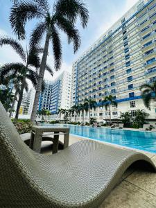 een stoel en een tafel naast een zwembad bij Sea Residences - Call Ang Alano in Manilla