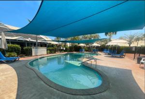 una gran piscina con una sombrilla azul. en Broome, en Broome