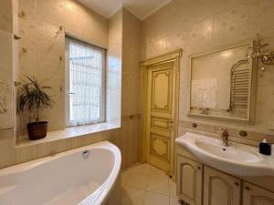 baño con bañera, lavabo y ventana en GoldenApartmentLviv, en Leópolis
