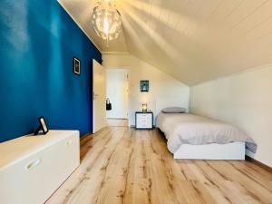 1 dormitorio con cama y pared azul en A La Côte en Neuchâtel