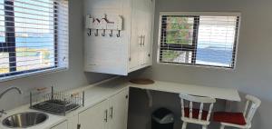 a kitchen with a counter and a sink and two windows at View on the Bay 7 Pinta Crescent in St Helena Bay