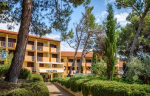 einen Blick nach außen auf ein Gebäude mit Bäumen in der Unterkunft San Marino Resort in Lopar