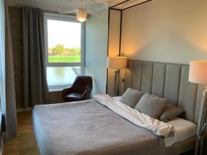 um quarto com uma cama, uma cadeira e uma janela em Riverside apartment self check-in em Klaipėda