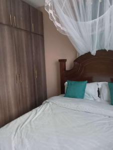1 dormitorio con 1 cama con cabecero de madera en LAURAPA home's, en Kisumu