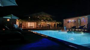 una piscina por la noche con sombrilla en Les Mazets Du Pas, en Gréoux-les-Bains